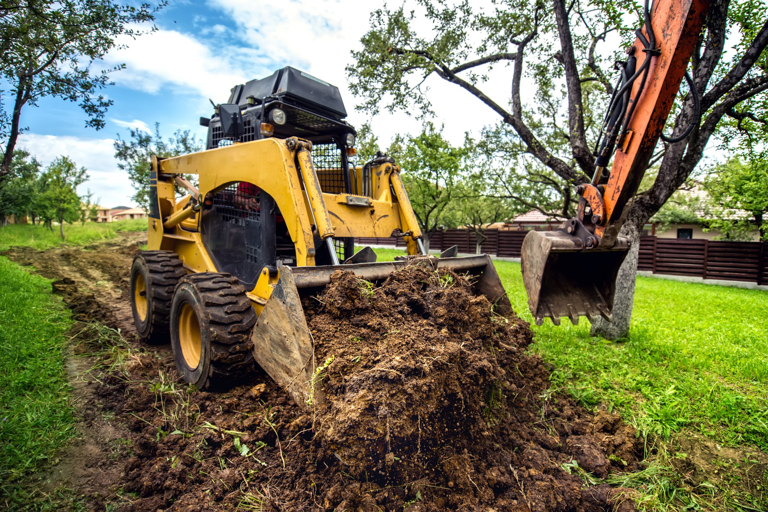 Yellow mini bulldozer working with earth, moving soil and doing landscaping works